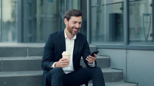Man in Suit Using Smartphone Outside Office Building