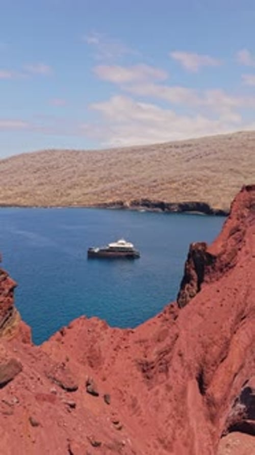 Vue aérienne verticale d'un catamaran planant le long de la côte rocheuse des Galapagos révélant un volcan