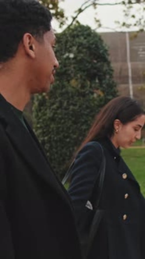 Young couple holding hands and walking in park.