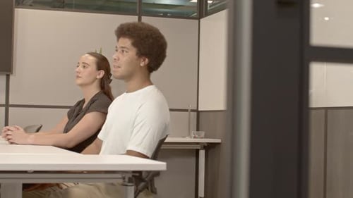 African American male in his 20's and a caucasian female in her 20's talking in business meeting wit