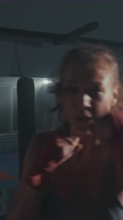 Séance d'entraînement intense mettant en vedette un boxeur pratiquant des techniques dans une salle de sport faiblement éclairée