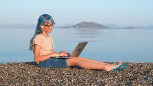 Young Woman Working on Laptop at Beach