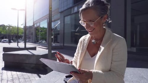Senior Business Woman Working with a Tablet Smiling in a Modern City
