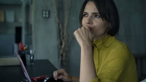 Thoughtful Woman Working on Laptop at Desk