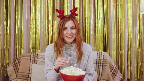 Woman Eating Popcorn Wearing Reindeer Antlers