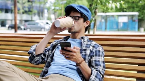 Man with Coffee Using Smartphone on Park Bench