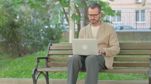 Young Man Working on Laptop while Sitting Outdoor