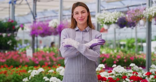 Smiling Woman in Sunny Greenhouse Surrounded by Flowers
