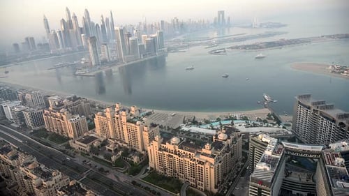 Experience an Aerial Perspective of Dubai City Juxtaposed Against a Body of Water During the
