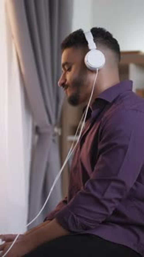 Young Adult Listening to Music With Headphones and Mug
