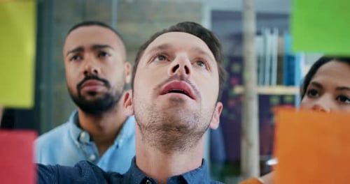 Team Collaborating Using Sticky Notes on Glass Wall