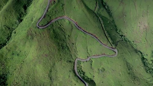Aerial Drone Footage of Winding Mountain Road Through Green Hills