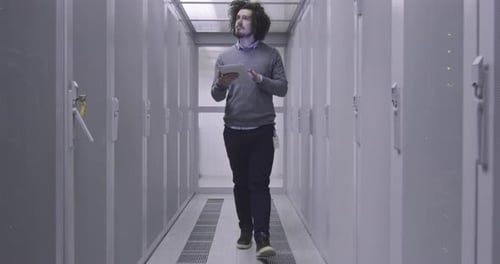 Man Walks Through Data Center with Tablet