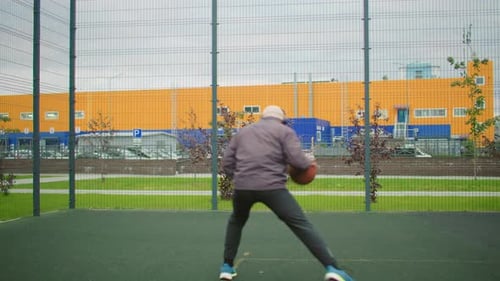 Man Dribbling Basketball on Outdoor Court