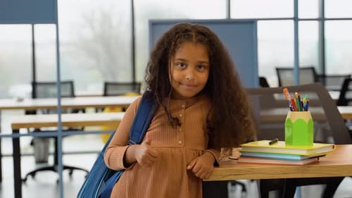 Student with Backpack Giving Thumbs Up in School