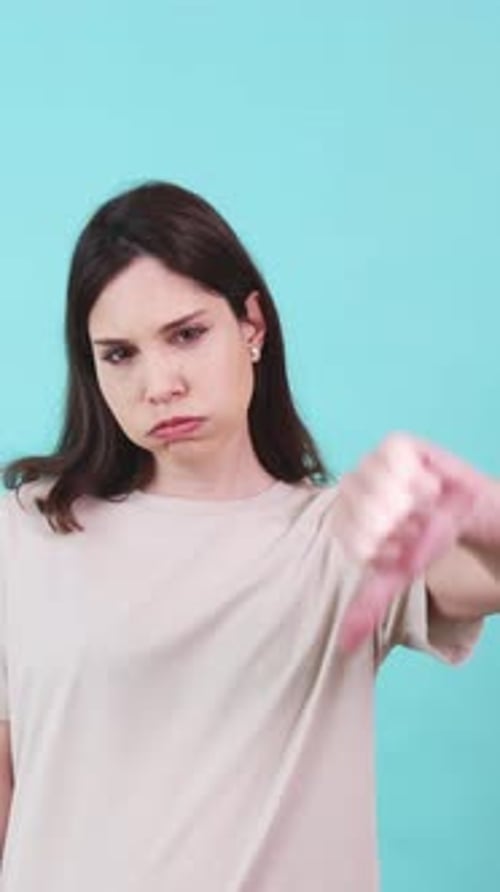 Young Woman with Thumbs Down on Blue Background