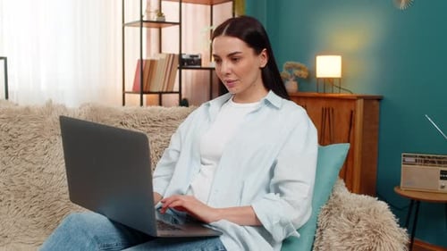 Woman Works On Laptop Sitting on Cozy Couch