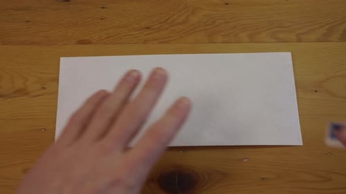 Man Places Stamp on Blank Envelope, First Person Point of View