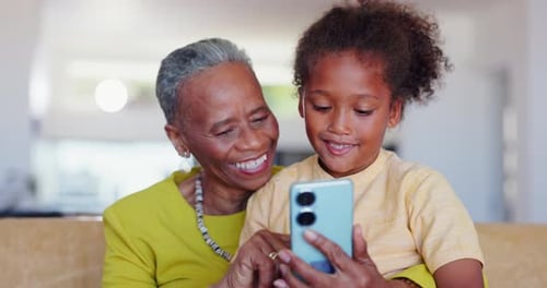Grandmother and Child Using Phone Together Indoors