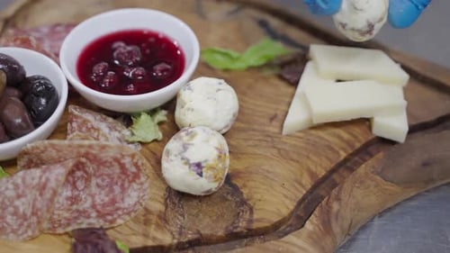 Ajouter des boulettes de fromage de chèvre dans une assiette de charcuterie.