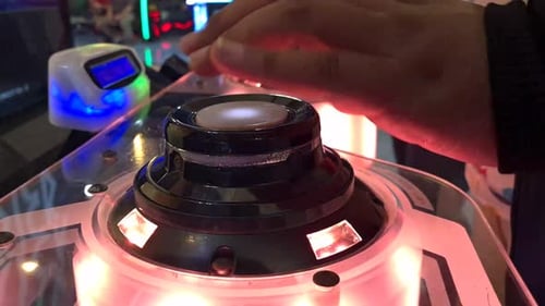 Close up hands pressing glowing button of rhythmical music Japanese arcade game