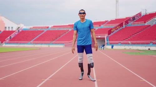 Asian para-athlete with prosthetic blades warms up body in the stadium.