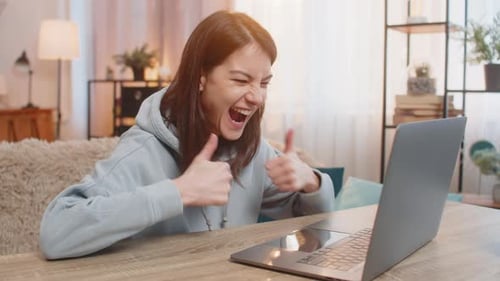 Woman Reacts with Excitement at Laptop at Home