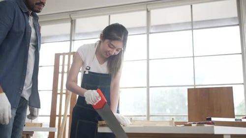 Woman Sawing Wood Under Supervision in Bright Studio