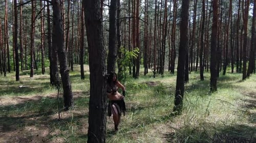 Aerial footage of a resting female barbarian with a sword in hand in the forest