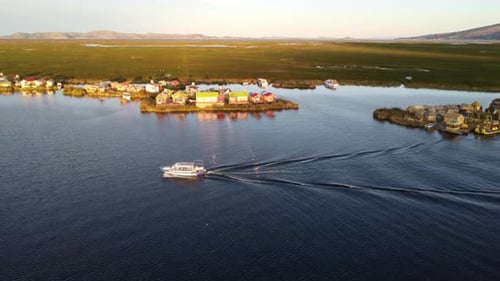 Boat driving on Lake Titicaca in Peru at sunset. Floating islands and reeds in background.