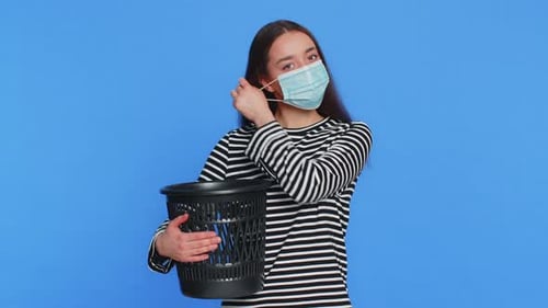 Woman Throwing Out Surgical Medical Protective Mask Into Bin After Pandemic Illness Sickness Ending