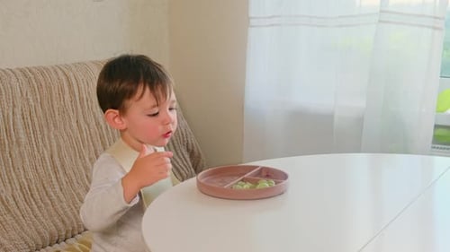 Child Eating Green Food at the Table