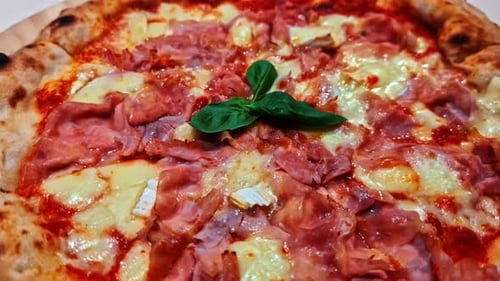 Close-up of a fresh ham and cheese pizza