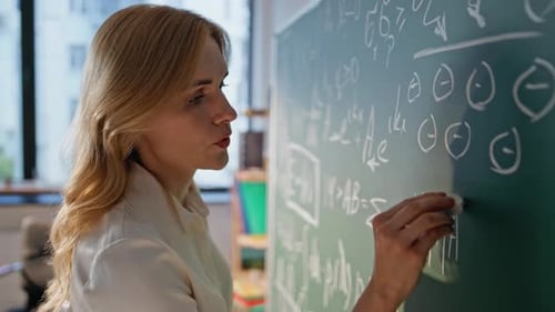 School Teacher Solving Math Equations on Blackboard with Chalk Closeup
