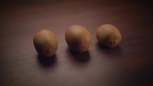 There are Three Kiwi Fruits Beautifully Arranged on a Wooden Surface for you to See and Enjoy