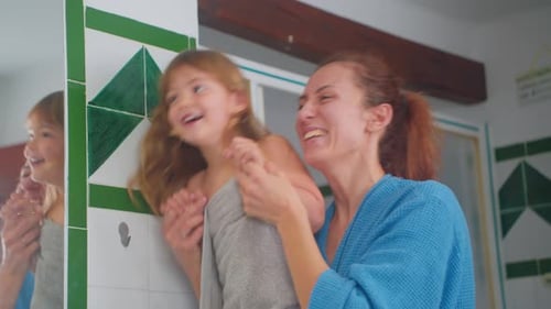 Loving Mother and Daughter Laughing Together in Bathroom