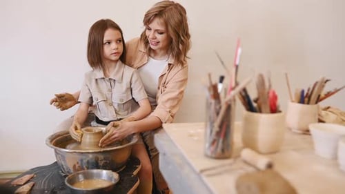 Woman Teaches Little Girl Pottery on Wheel