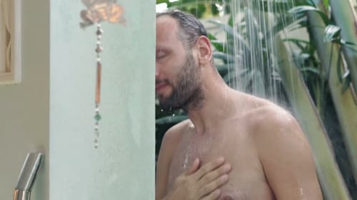 Man enjoying cool refreshing outdoor shower in tropics
