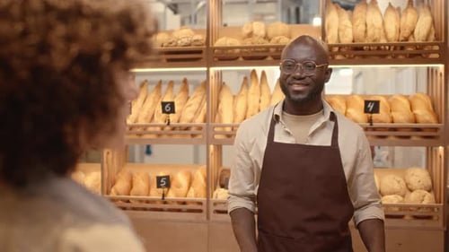 Bakery Salesman Speaking with Female Customer at Counter