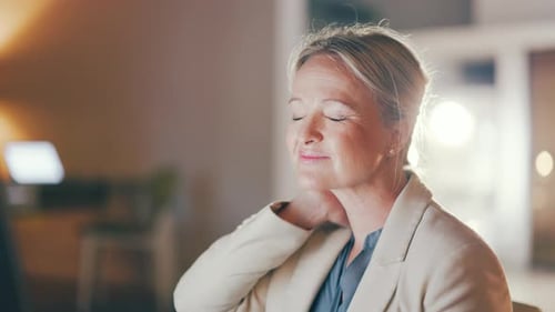 Businesswoman Stretches Neck While Working at Night