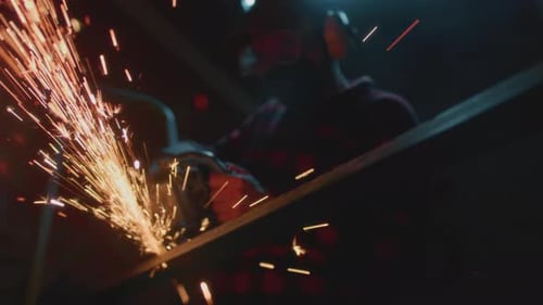 Man Working at Factory Cuts Metal with a Grinder Male at a Construction Site Cuts Off Piece Guy