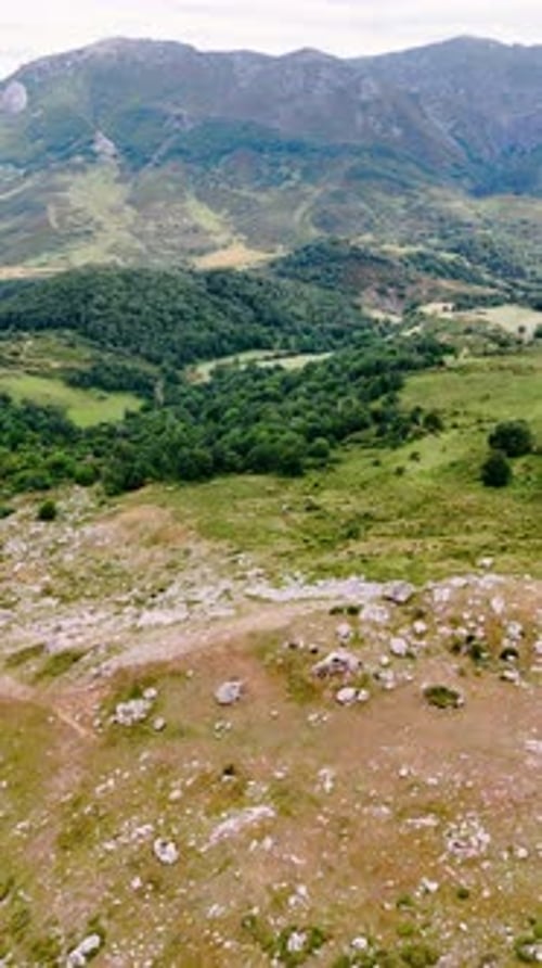 Flight above the wilderness in rocky scenery. Aerial view on the lake in the mountains at backdrop.