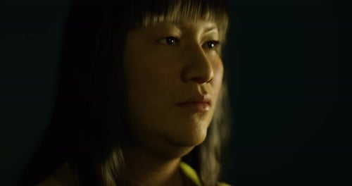 Woman with Long Hair Gazes Thoughtfully Into the Distance Under Soft Lighting