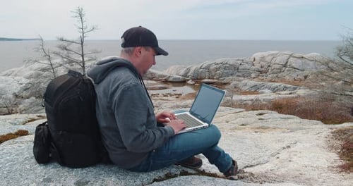 Blogger Freelancer Sitting on Top of a Mountain and Working on Laptop