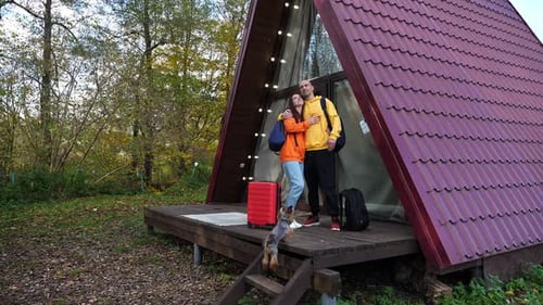 Young Couple Embracing at Cabin with Dog