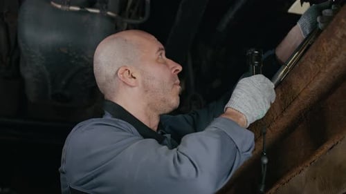 Technician Repairing Vehicle Undercarriage with Flashlight