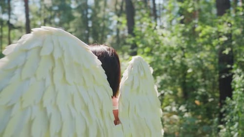 Gros plan d'une fille souriant chaleureusement se retournant dans une forêt ensoleillée