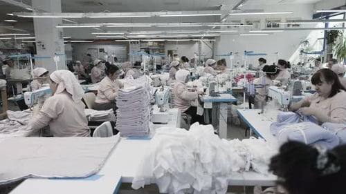 Die Arbeiter in der Textilfabrik sind damit beschäftigt, Stoffe für die Herstellung von Kleidungsstücken an der Produktionslinie zu nähen