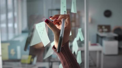 Businesswoman Writing on Sticker Note in Office