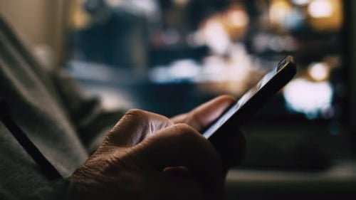 Hands Using Phone in Dimly Lit Home